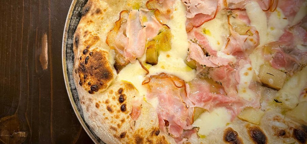 Cameriere che serve una pizza al tavolo in pizzeria a Barcellona Pozzo di Gotto